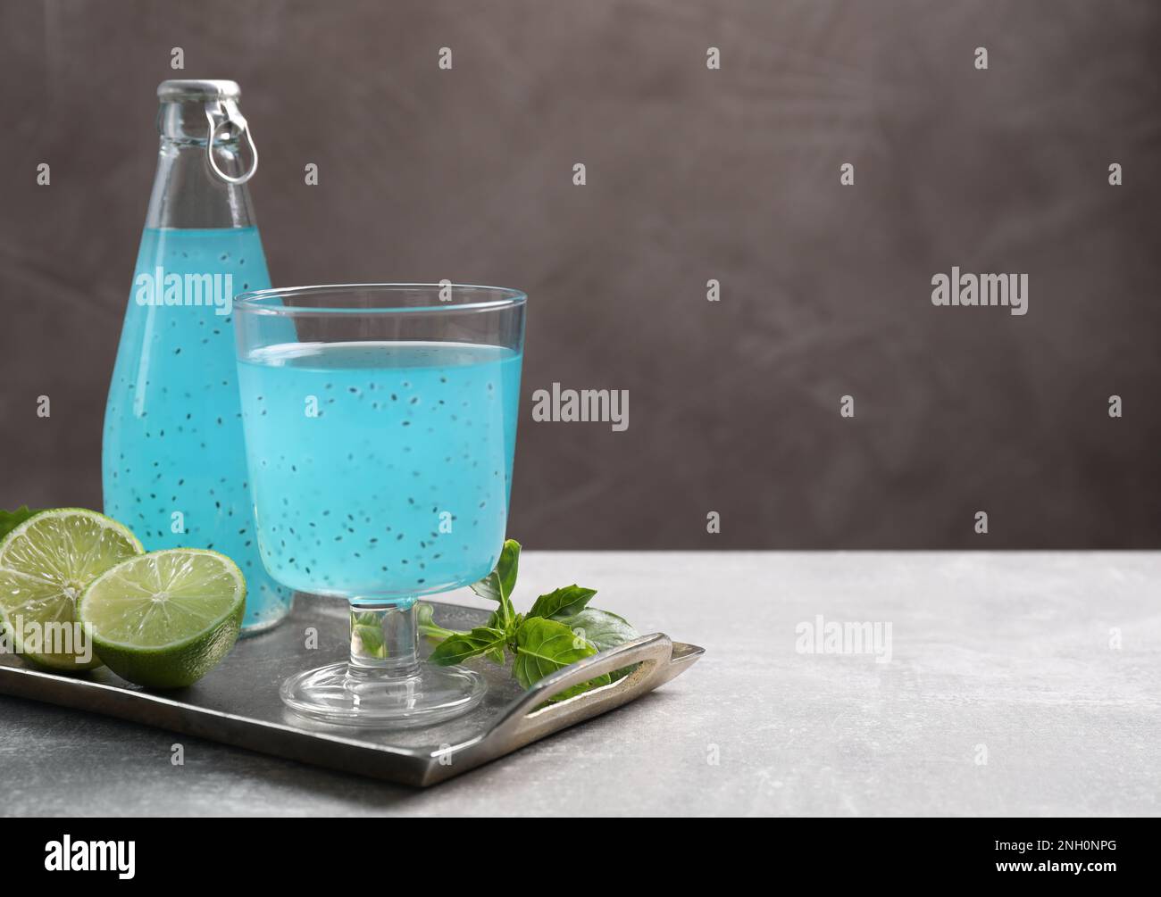 Savoureuse boisson bleu clair avec des graines de basilic sur table grise, espace pour le texte Banque D'Images