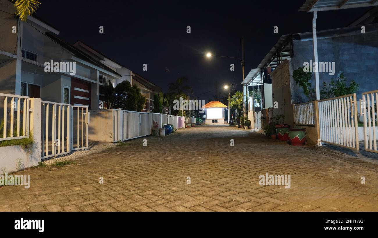 Paysage de nuit vide solitaire et tranquille pavant rue de la maison résidentielle à village rural avec Crescent lune Banque D'Images