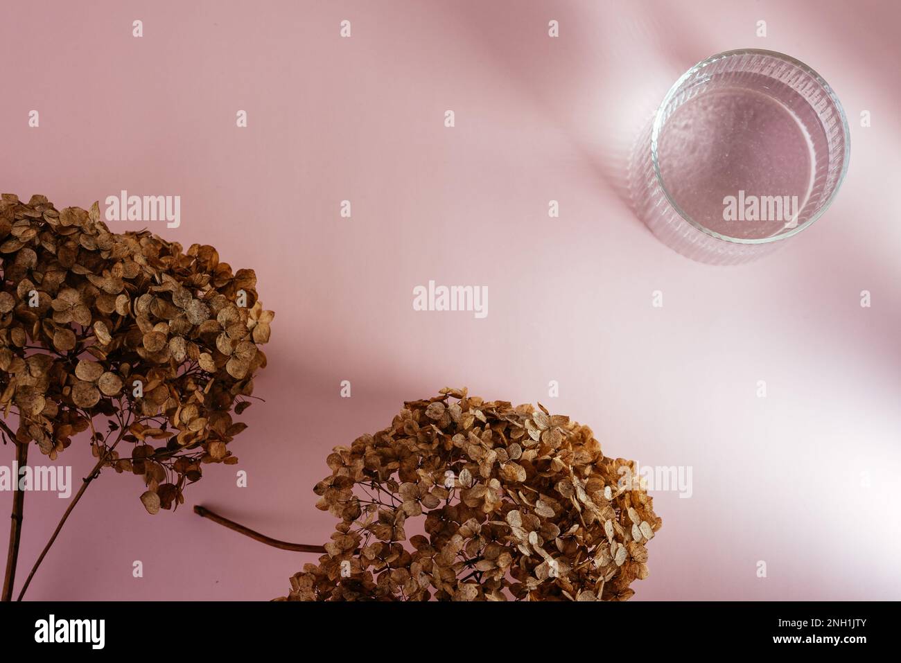 un verre avec de l'eau sur la table. fond rose Banque D'Images