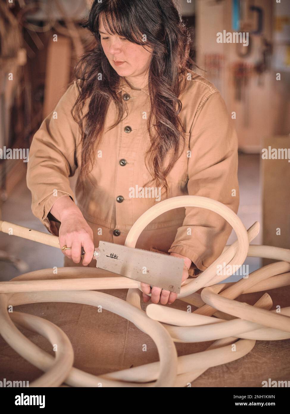 Une artiste féminine de son studio travaille avec l'une de ses sculptures en bois Banque D'Images
