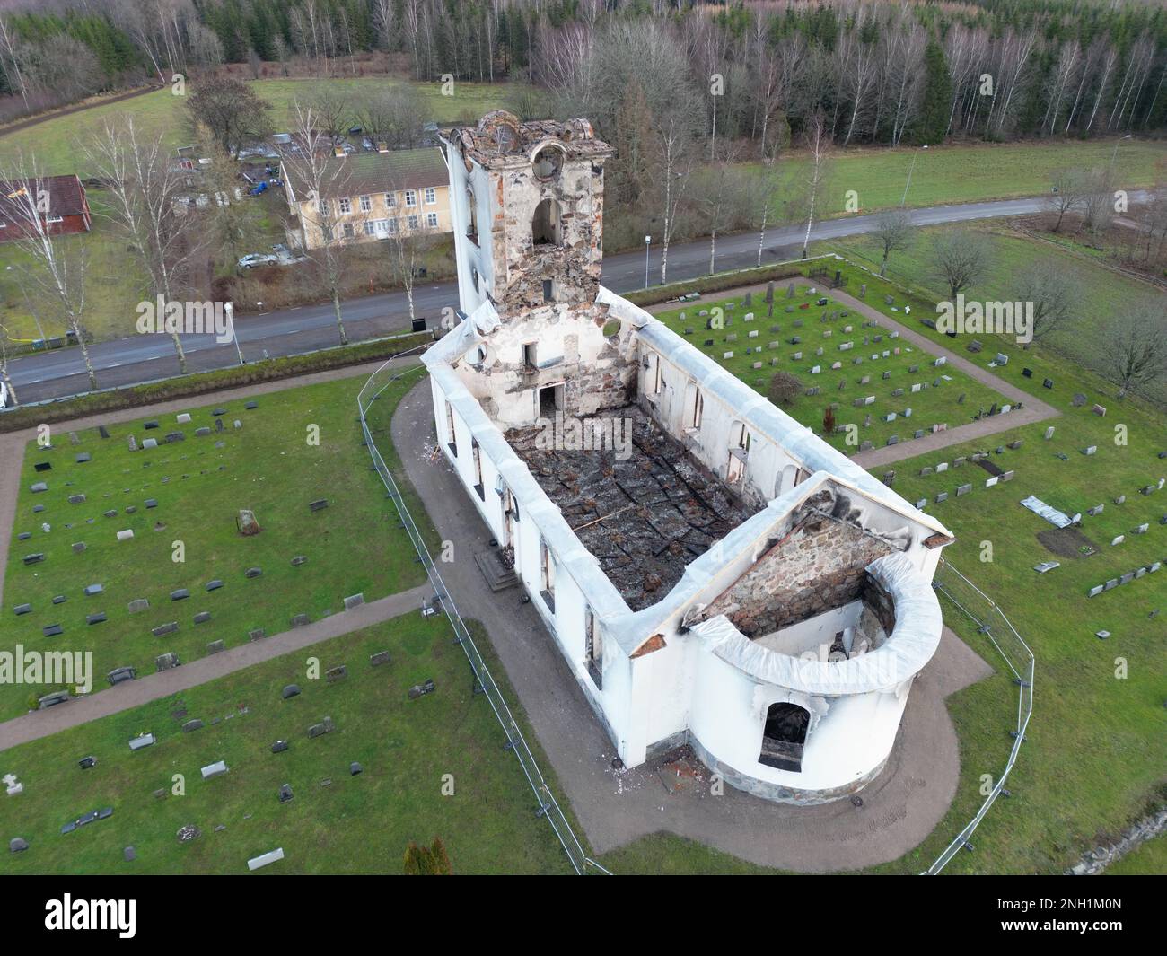 Vue aérienne d'une ancienne chapelle en ruines, entourée d'une végétation luxuriante et d'un cimetière de pierres tombales Banque D'Images