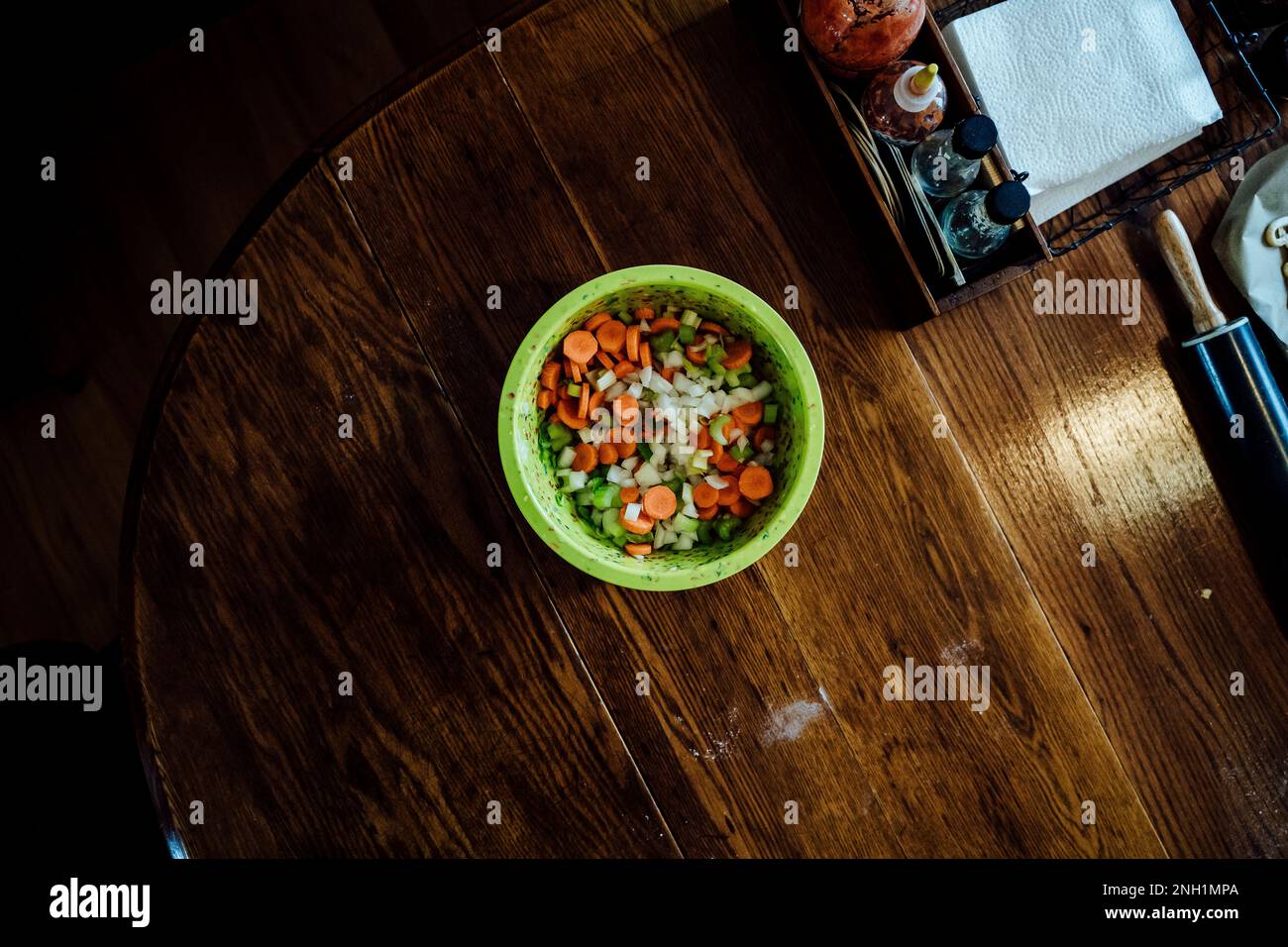 Bol vert vif de légumes hachés sur une table de cuisine en bois foncé Banque D'Images