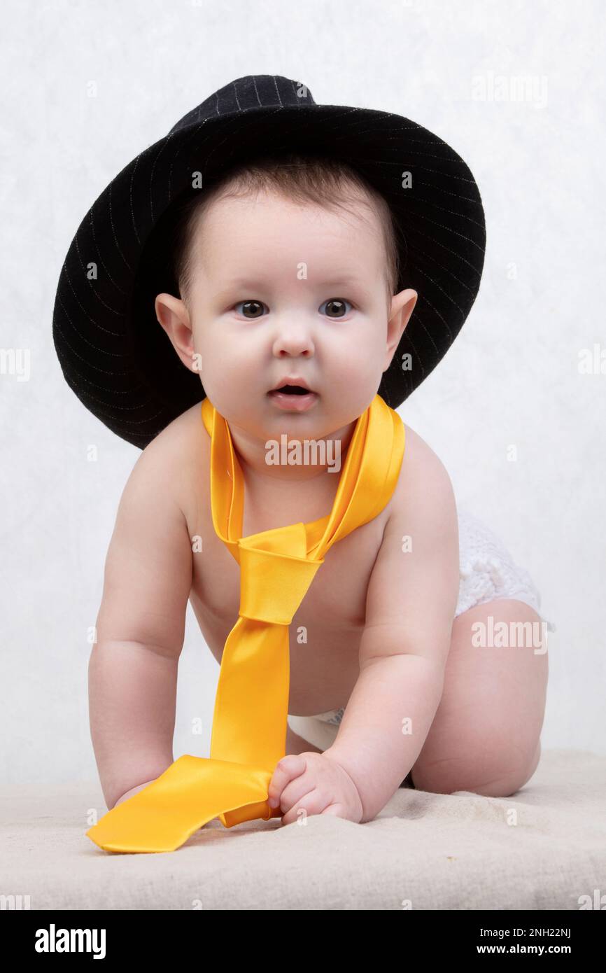 Enfant souriant dans un chapeau rétro et cravate sur un fond blanc. Drôle  de bébé de six mois dans des vêtements élégants Photo Stock - Alamy