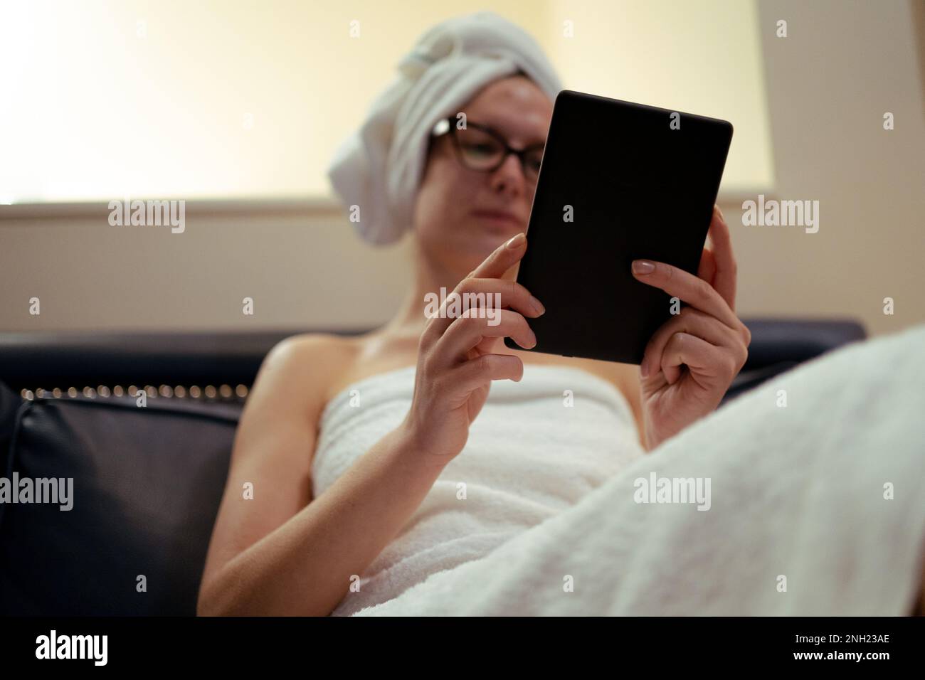 femme de lunettes de vue lisant un ebook détendu après la douche, la routine de beauté, à la maison Banque D'Images