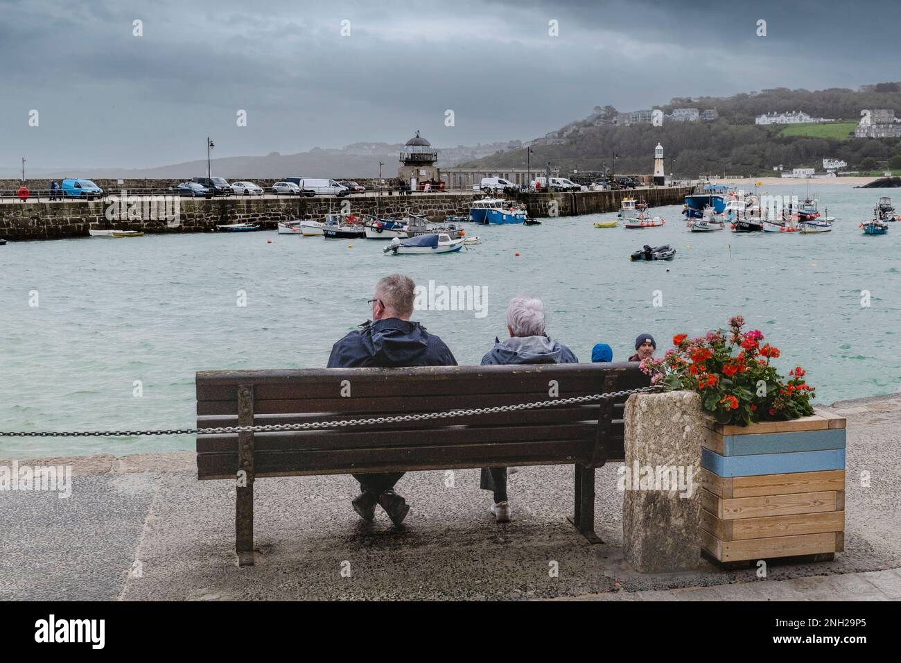 Météo au Royaume-Uni. Les visiteurs assis sur un banc lors d'une journée pluvieuse et misérable dans la ville balnéaire historique de St Ives, en Cornouailles, en Angleterre, au Royaume-Uni. Banque D'Images