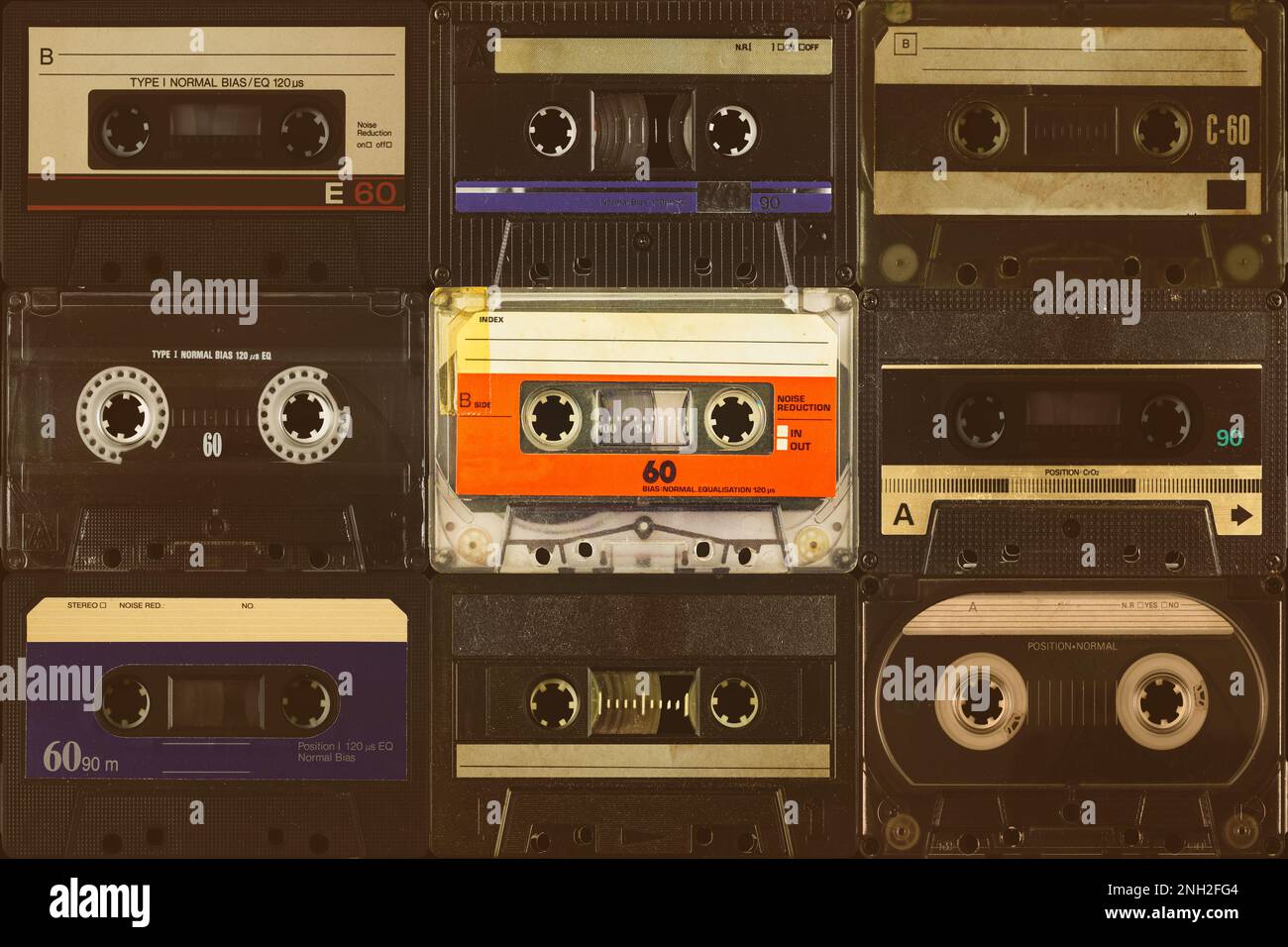 Une cassette compacte orange vintage colorée devant des cassettes audio noires Banque D'Images