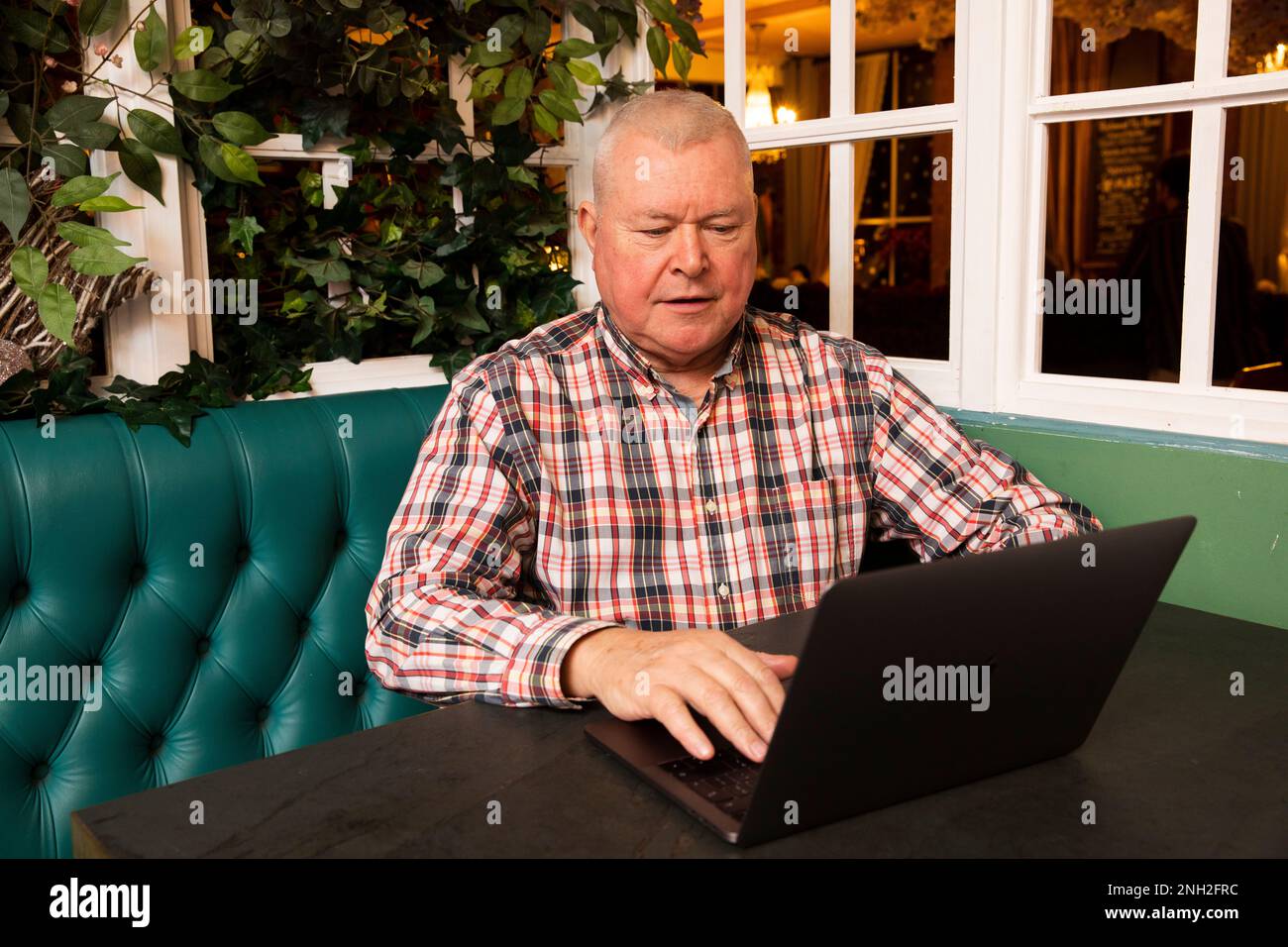 Homme dans son 60s avec un ordinateur portable assis dans un café. Manchester. Royaume-Uni. Banque D'Images