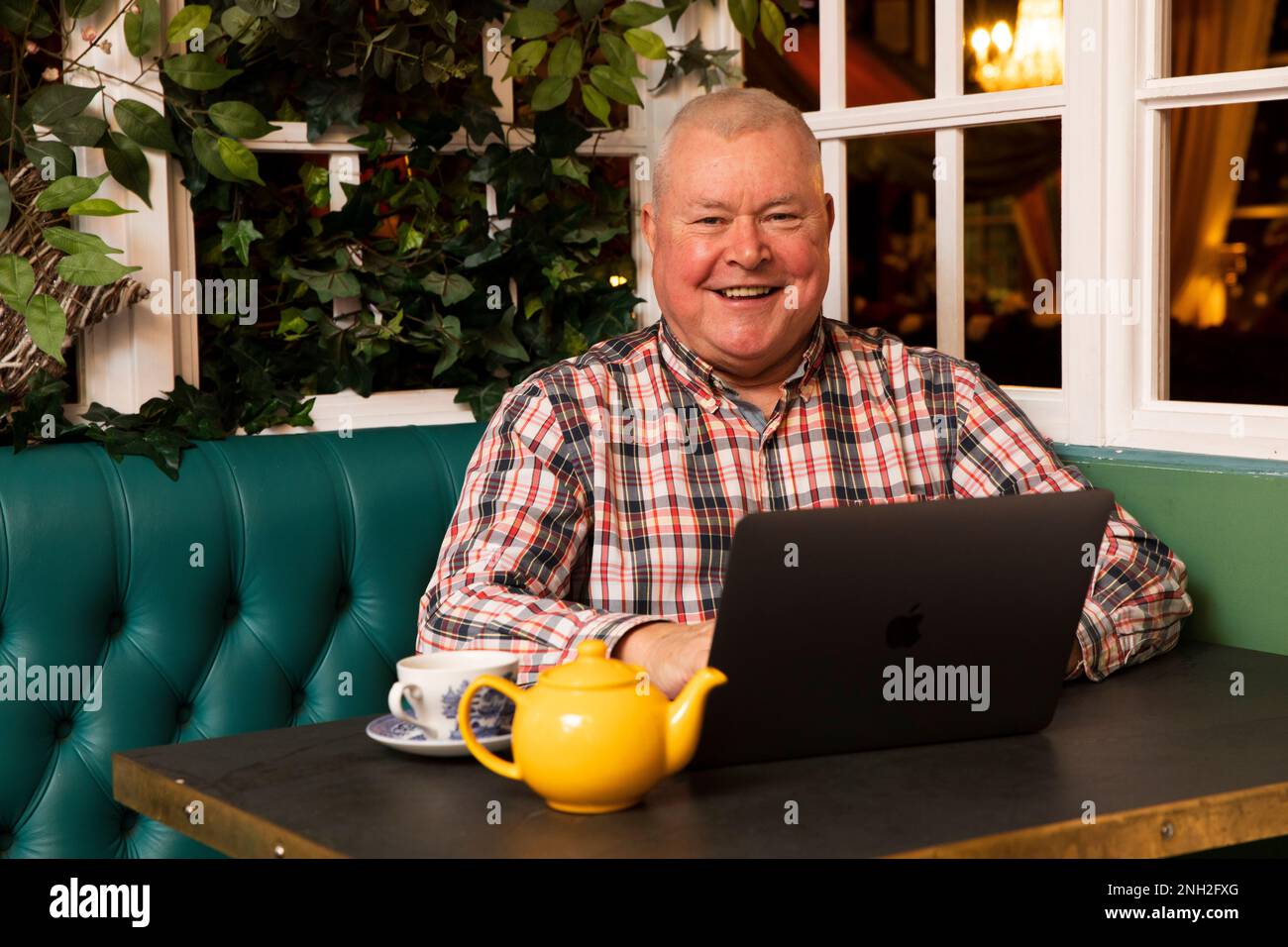 Homme dans son 60s avec un ordinateur portable assis dans un café. Manchester. Royaume-Uni. Banque D'Images