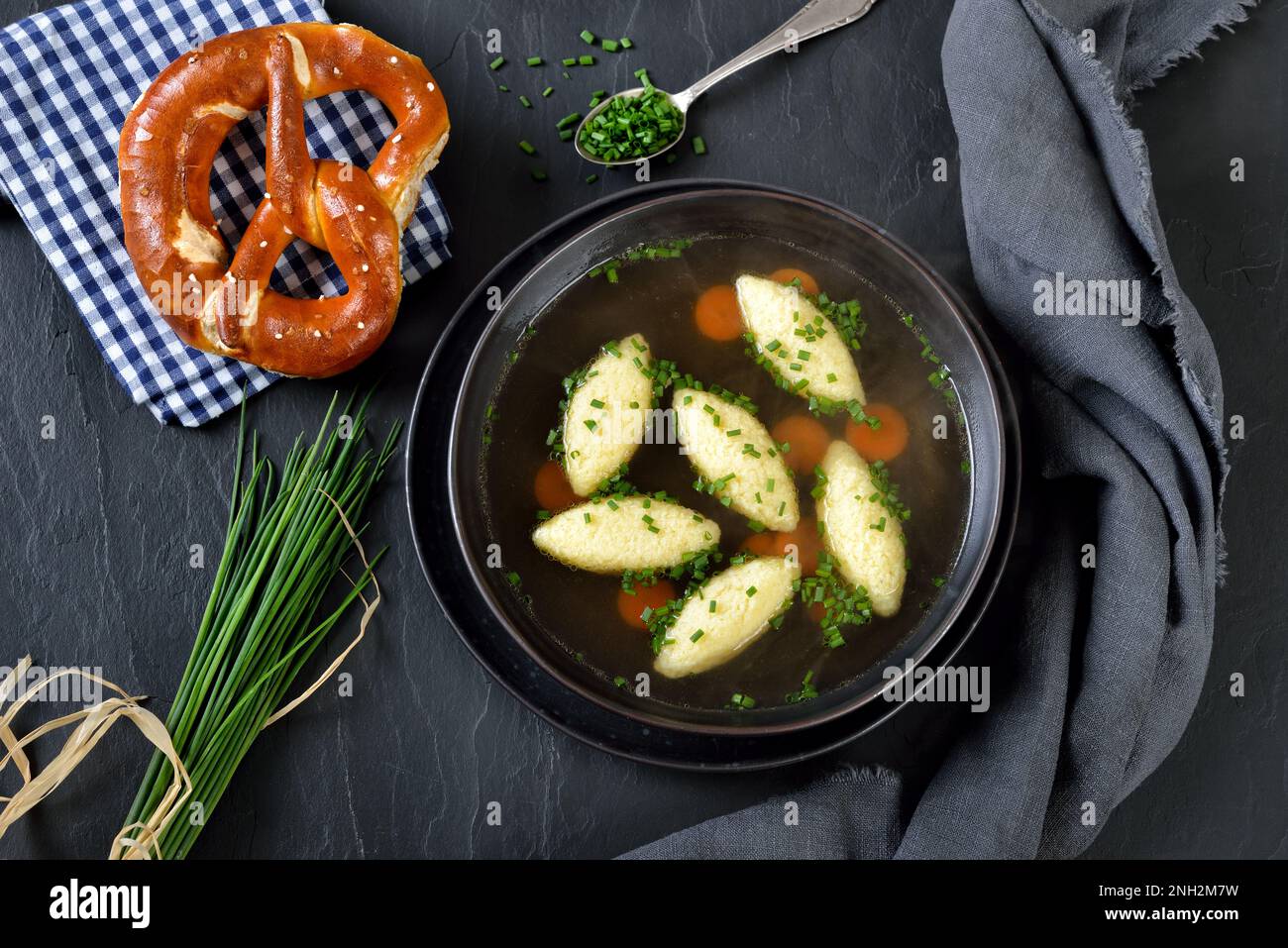 Plats bavarois, souabe et autrichiens - boulettes de semoule dans un bouillon de légumes, servies avec un bretzel croustillant Banque D'Images