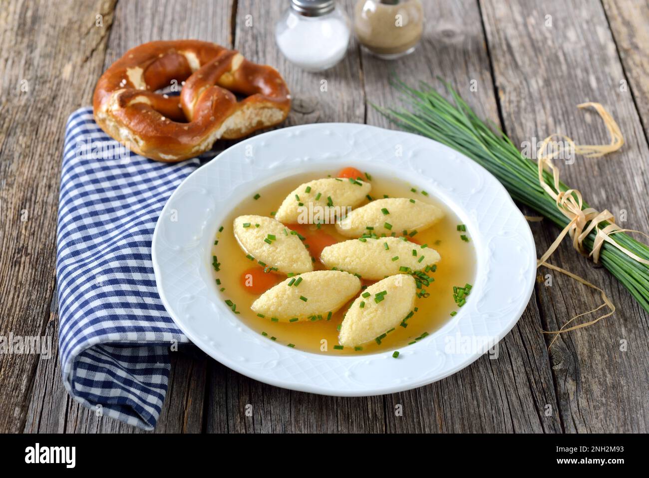 Plats bavarois, souabe et autrichiens - boulettes de semoule dans un bouillon de légumes, servies avec un bretzel croustillant Banque D'Images