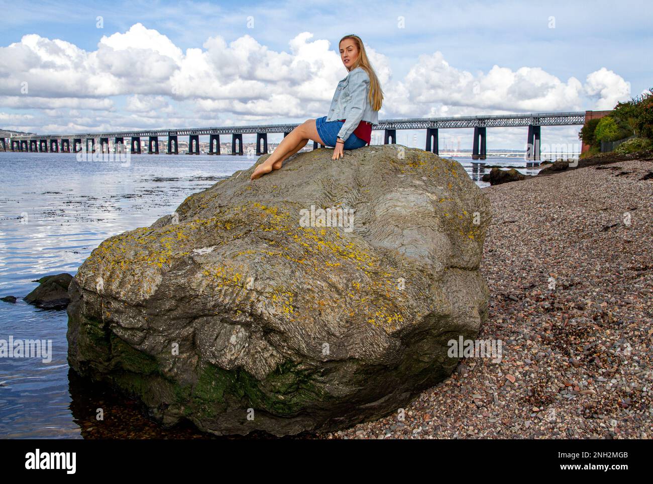 Lors d'une belle journée d'octobre à Wormit Beach, Fife, Rhianna Martin se trouve sur de grandes rochers au bord de la rivière Tay, en Écosse Banque D'Images
