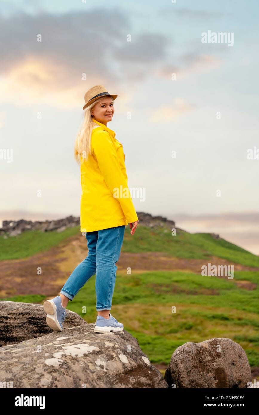 Femme en manteau jaune atteignant la destination et assis sur des chaises de plage au sommet de la colline ou de la montagne au lever du soleil. Hiver froid britannique. Centre touristique local Banque D'Images