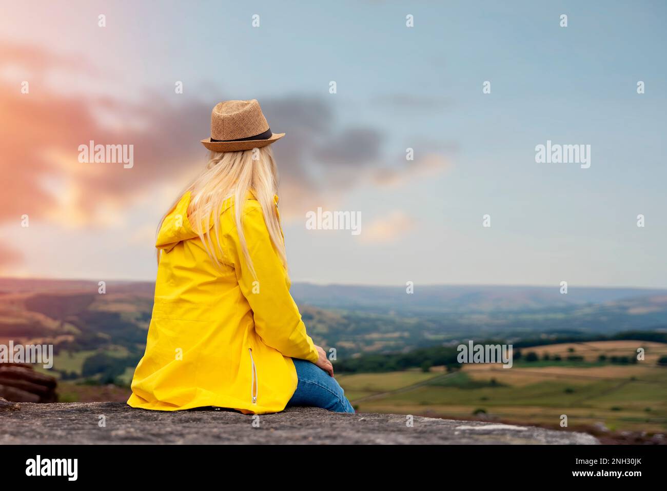 Femme en jaune coa atteignant la destination et assis sur des chaises de plage au sommet de la colline ou de la montagne au lever du soleil. Hiver froid britannique. Tourisme local con Banque D'Images