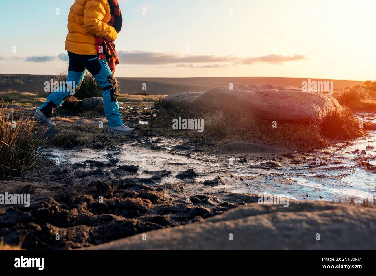 Femme en manteau jaune et foulard orange marchant et atteignant la destination au sommet de la colline ou de la montagne au lever du soleil. Hiver froid britannique. Le tourisme local c Banque D'Images