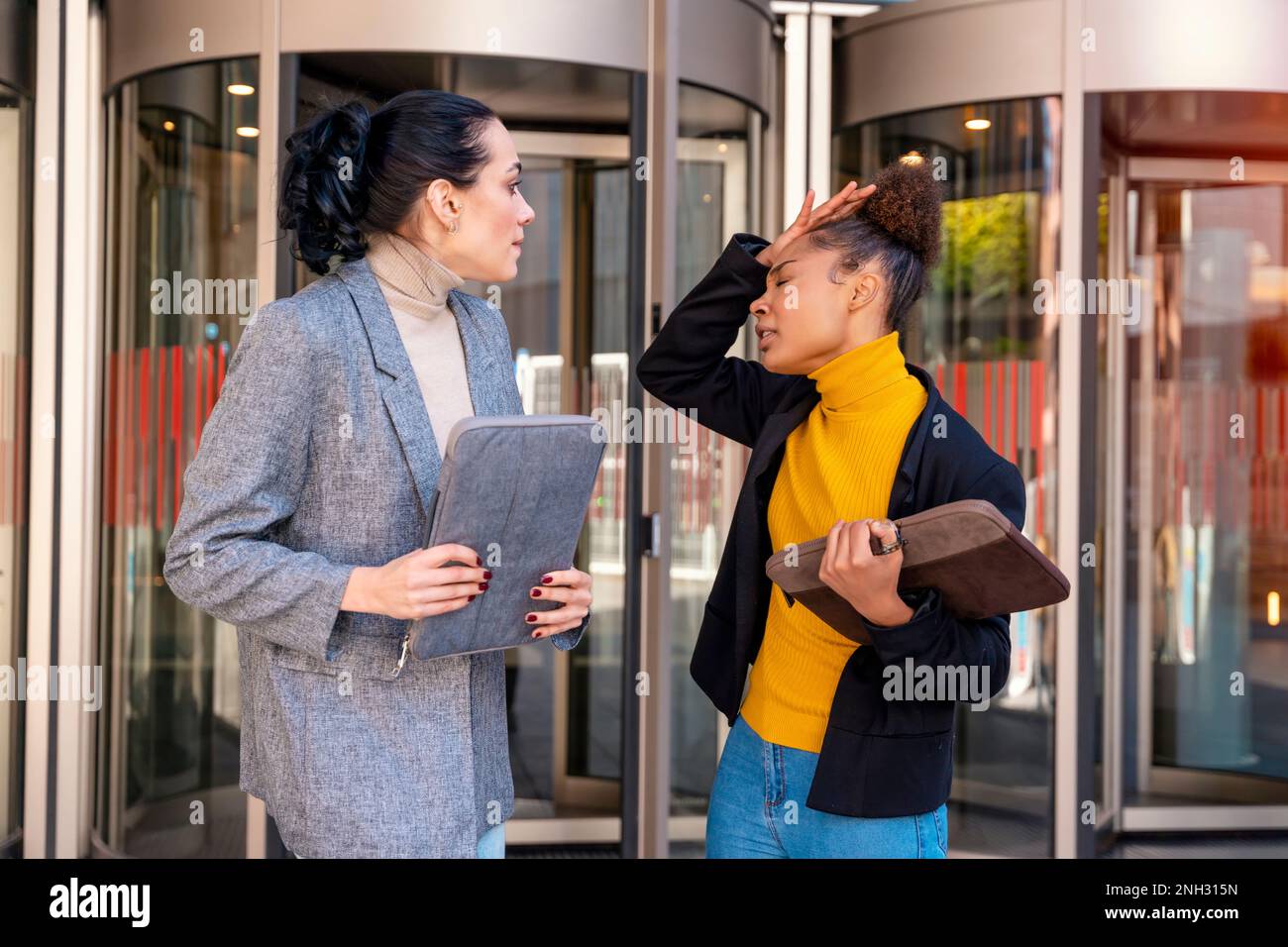 Deux femmes d'affaires malheureuses portant des tenues de bureau avec des tablettes numériques, argumentent. concept de partenaires commerciaux Banque D'Images