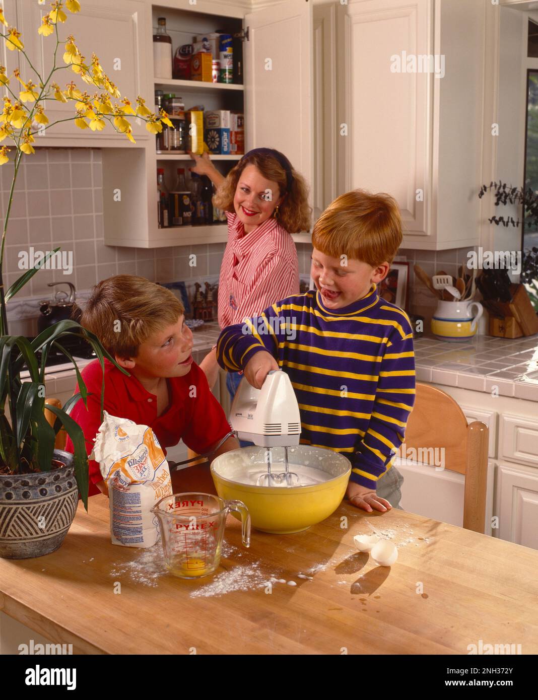 Mère avec deux fils dans la cuisine four et mélanger la pâte avec un batteur Banque D'Images