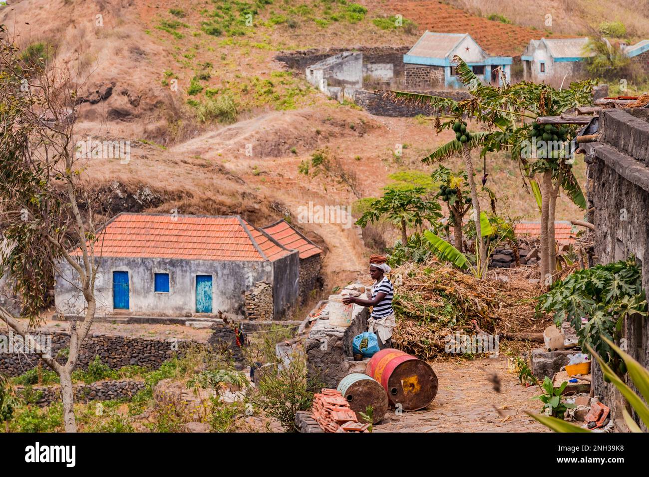 Une femme au travail devant une maison simple dans le centre accidenté et montagneux de l'île de Santiago, les îles du Cap-Vert, la Macaronesia Banque D'Images