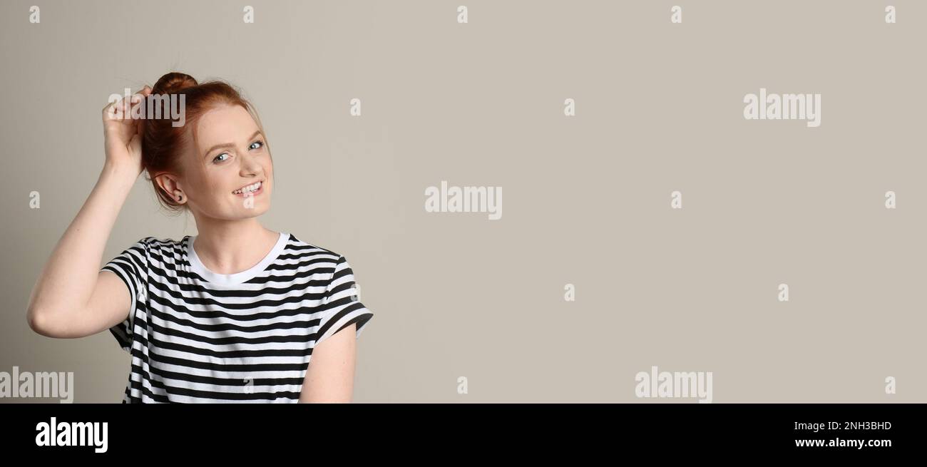 Portrait franc de la femme heureuse aux cheveux rouges avec un sourire charmant sur fond beige, espace pour le texte Banque D'Images