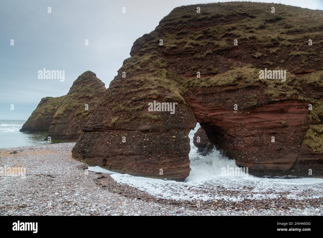 Vagues s'écrasant à travers une arche nautrale le long du sentier côtier Angus. Banque D'Images