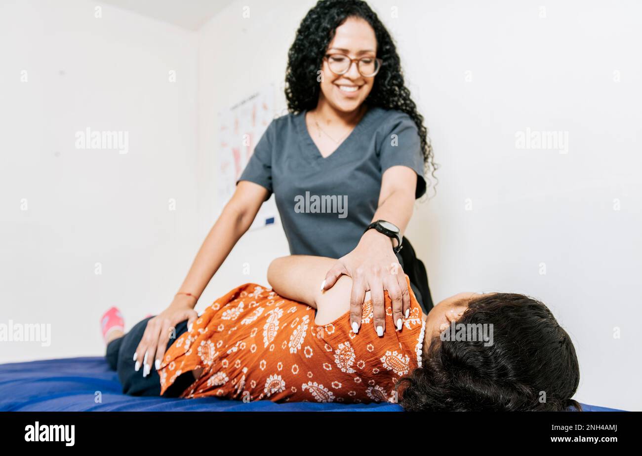 Femme en physiothérapie de réadaptation d'épaule. Physiothérapeute réhabilitant l'épaule à la patiente couchée sur le côté. Traitement des épaules et du dos Banque D'Images