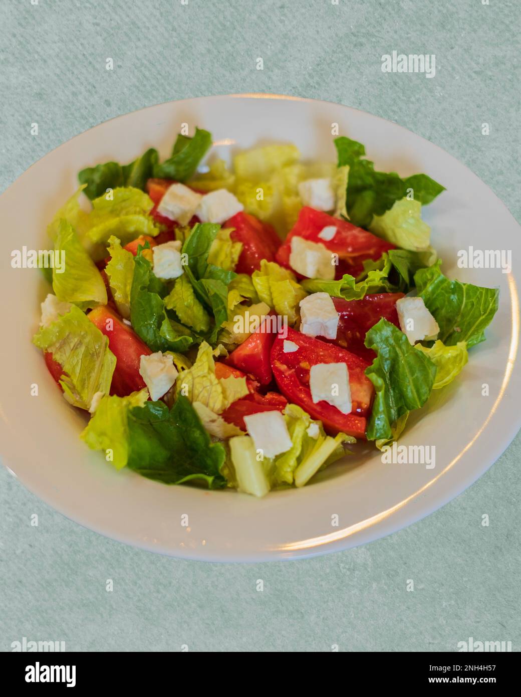 Une salade fraîche avec de la laitue romaine, des tomates coupées et du fromage feta dans un bol blanc. Gros plan, par le dessus. Banque D'Images
