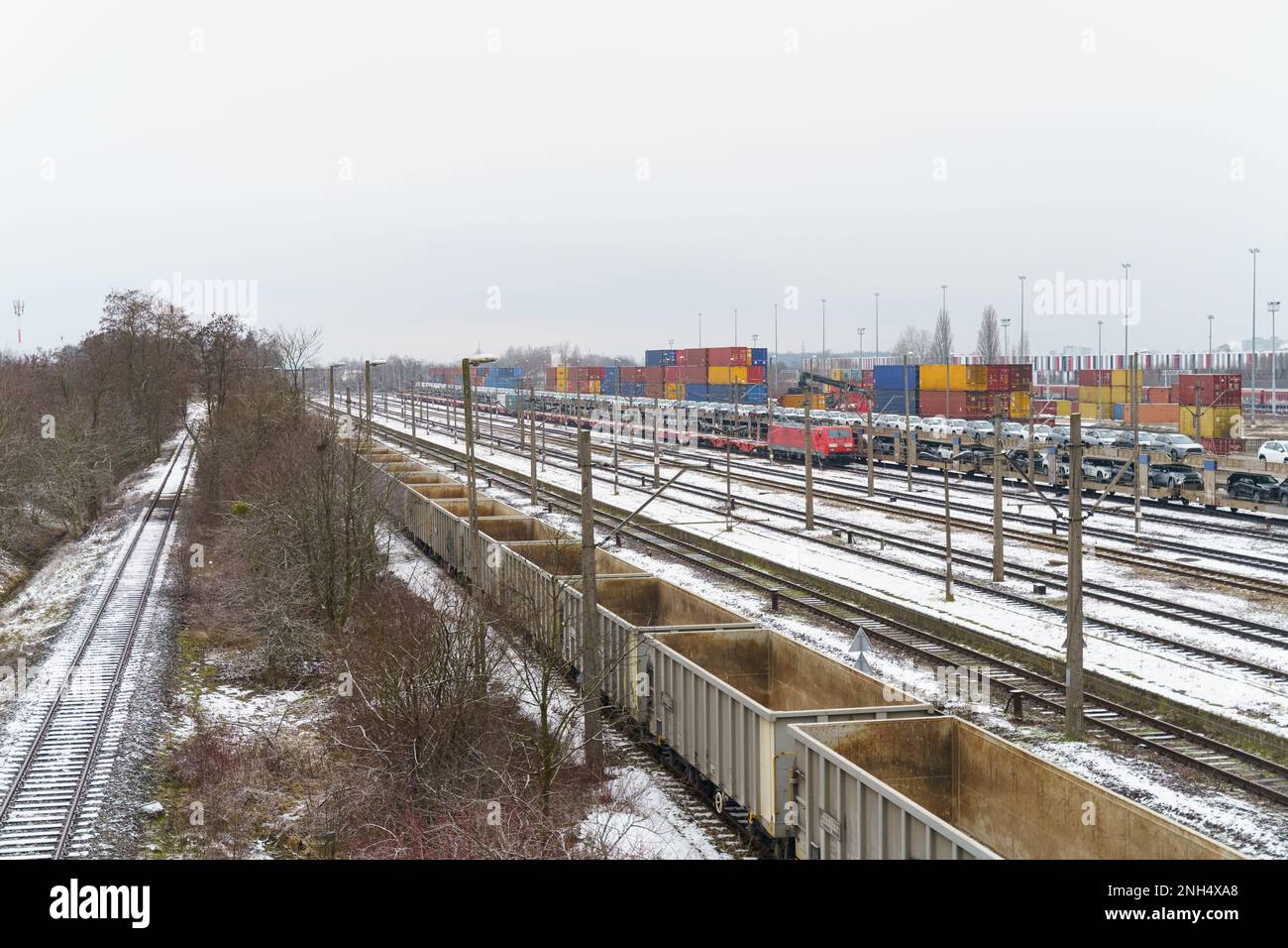 Gare de déchargement et de chargement de fret. Sur la plate-forme il y a des wagons avec des voitures, des wagons vides, des conteneurs déchargés à proximité sur la plate-forme. Banque D'Images