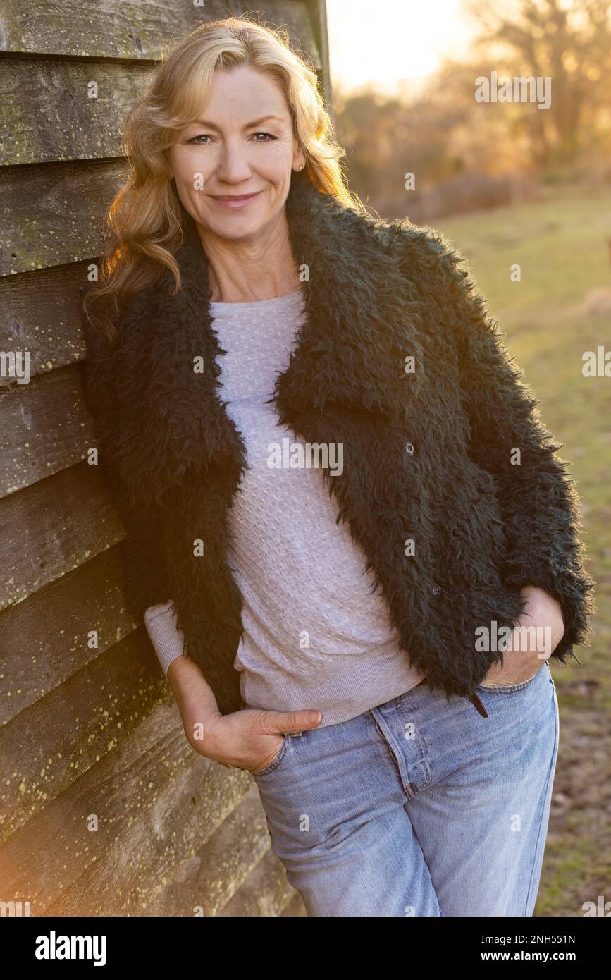 Belle femme d'âge moyen attentionnés souriant dehors au coucher du soleil Banque D'Images