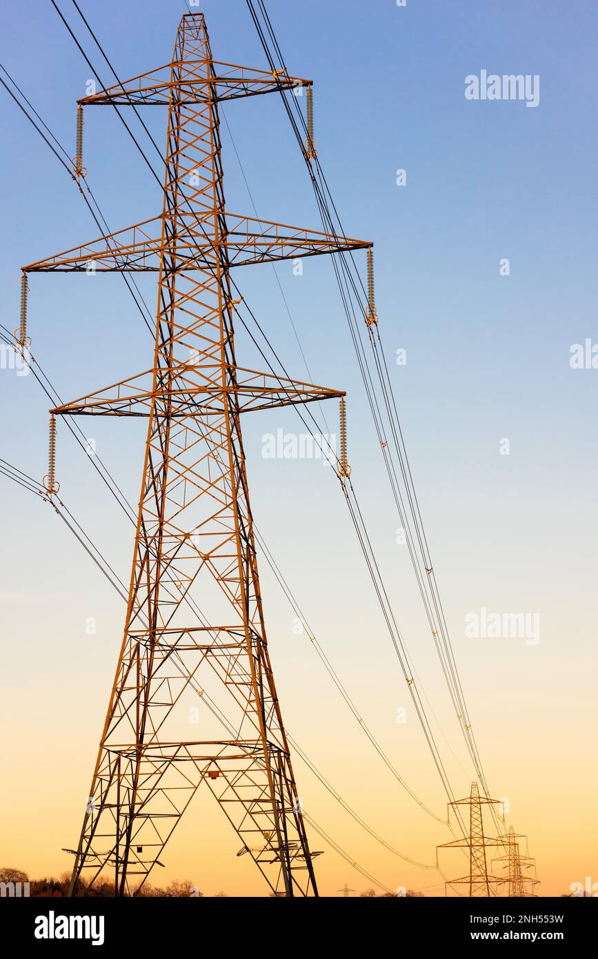 Pylônes d'électricité du réseau national au coucher du soleil ou au lever du soleil Banque D'Images