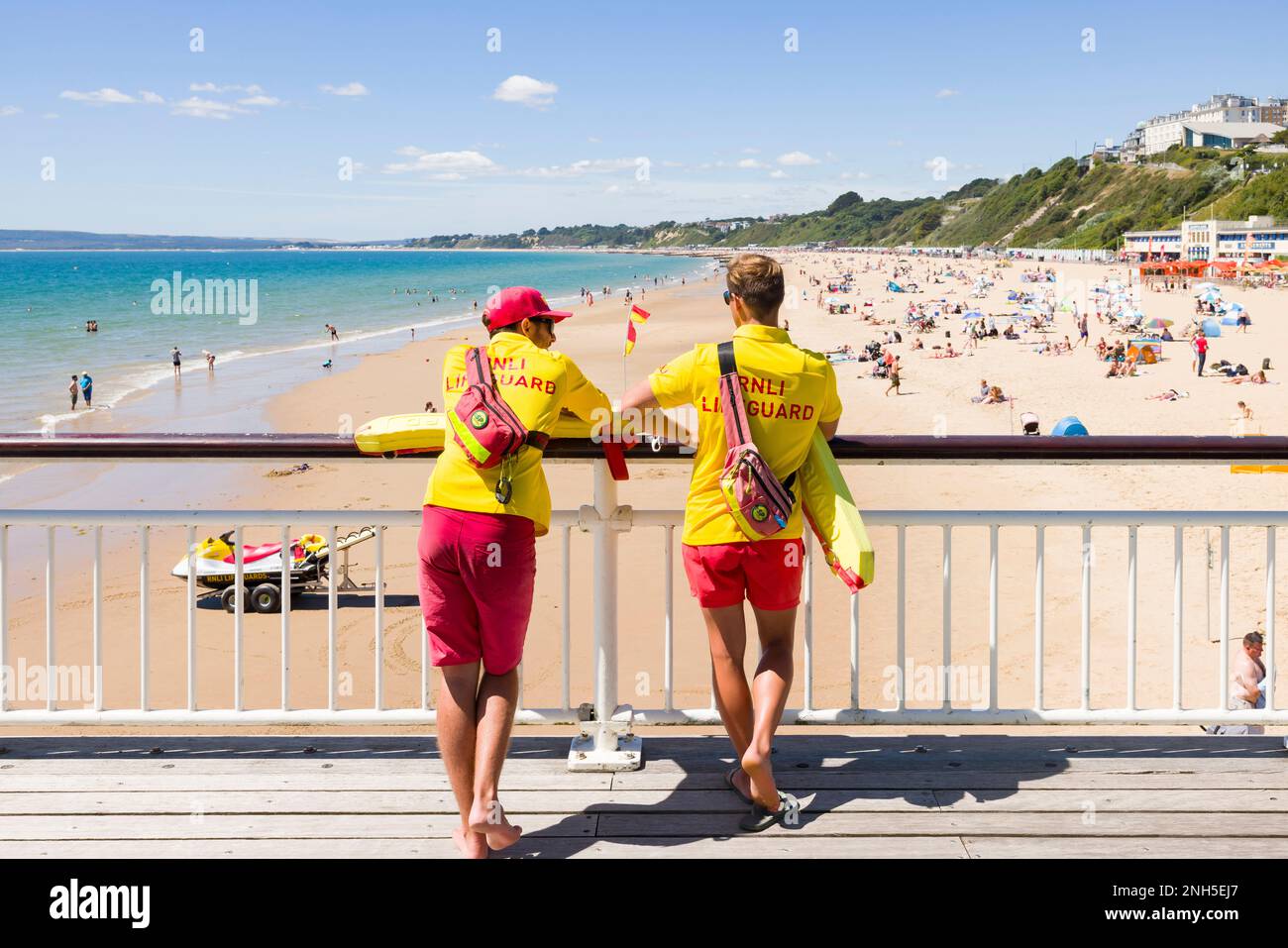 BOURNEMOUTH, Royaume-Uni - 08 juillet 2022. Deux sauveteurs RNLI en uniforme observant la plage de Bournemouth depuis la jetée pendant l'été. Banque D'Images