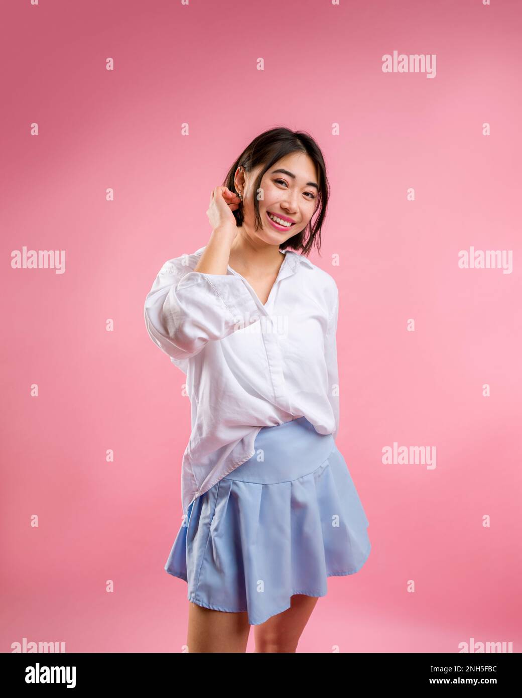 3/4 Body Asian Femme debout appareil photo blanc Chemisier Bleu jupe courte face appareil photo Rose toile de fond | espace copie Banque D'Images