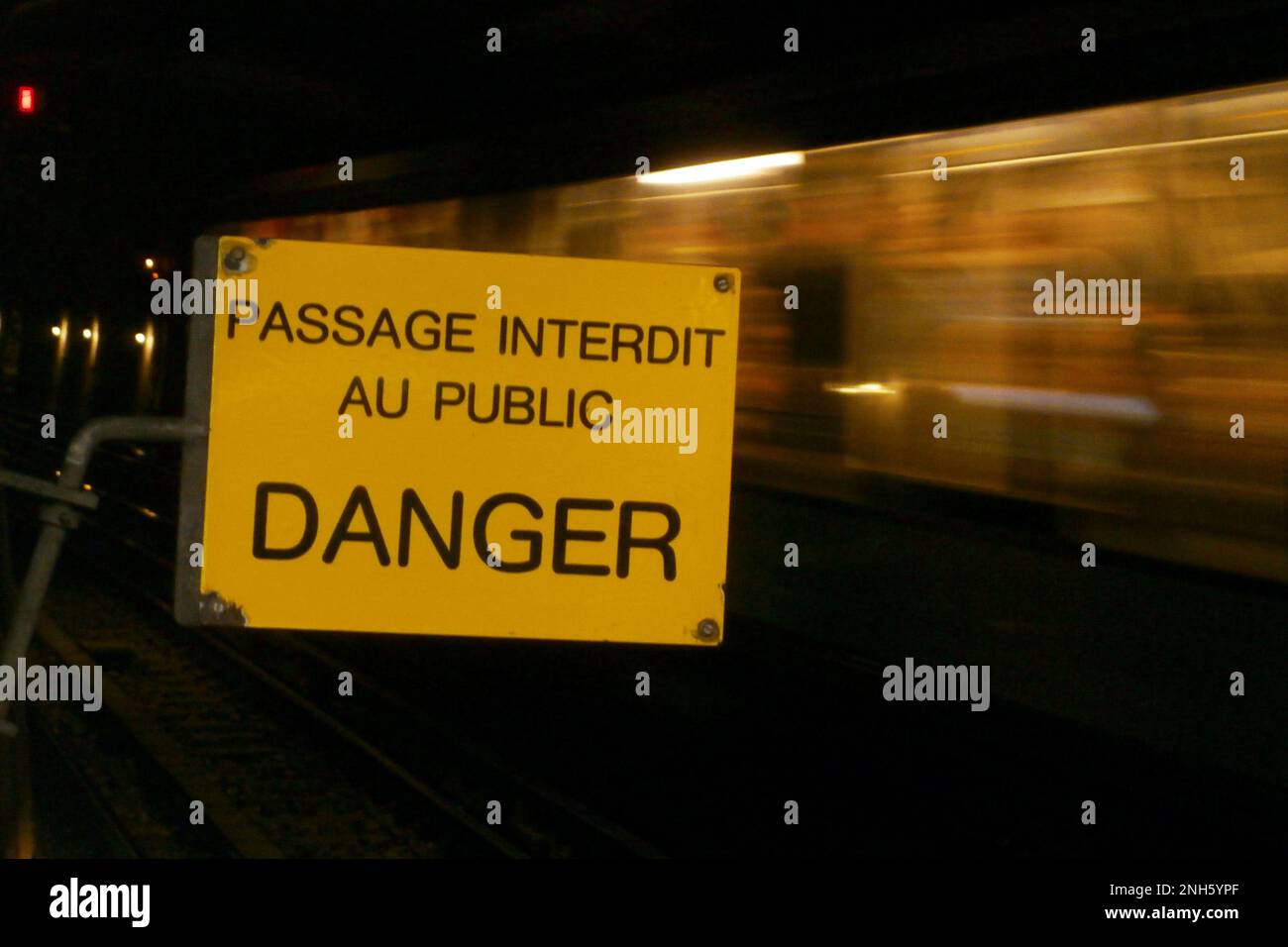 Panneau d'avertissement jaune dans le métro de Paris avec écrit en français dans son milieu 'passage interdit au DANGER public', signifiant en anglais 'passage interdit ite Banque D'Images