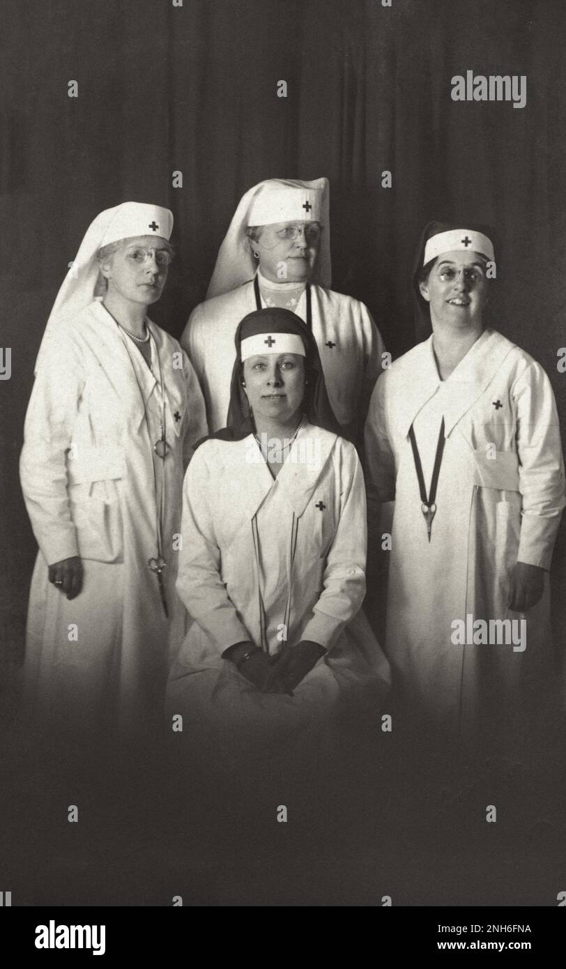 Première Guerre mondiale Carte postale comportant une photo en noir et blanc de quatre infirmières (canadienne?) en uniforme. L'un est assis devant, trois autres debout à côté d'elle. Ils portent des foulards rouges à la tête. 1917-1918 Banque D'Images