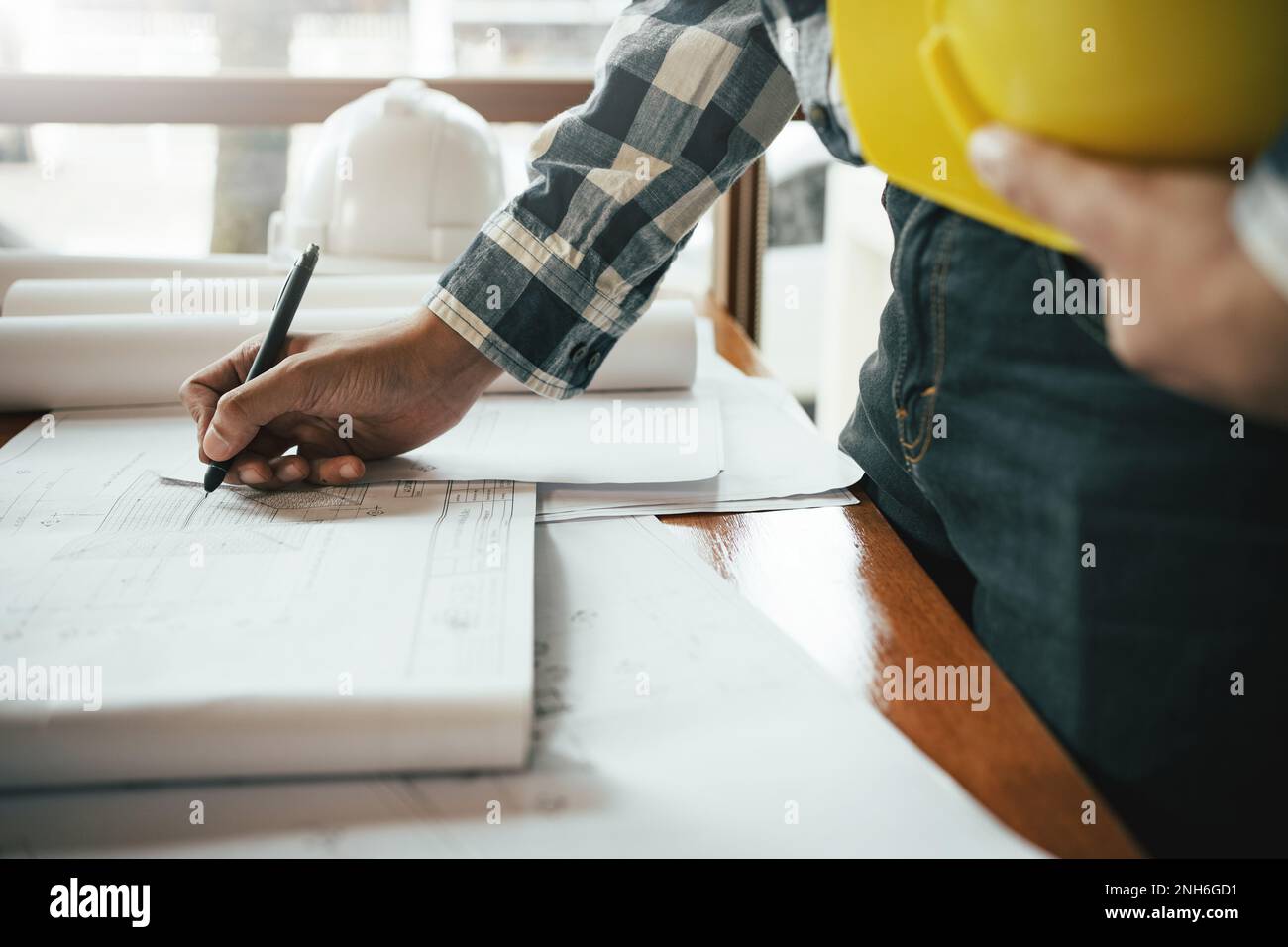 Gros plan d'un ingénieur civil asiatique travaillant sur un projet d'architecture de plan sur le chantier de construction au bureau. Banque D'Images