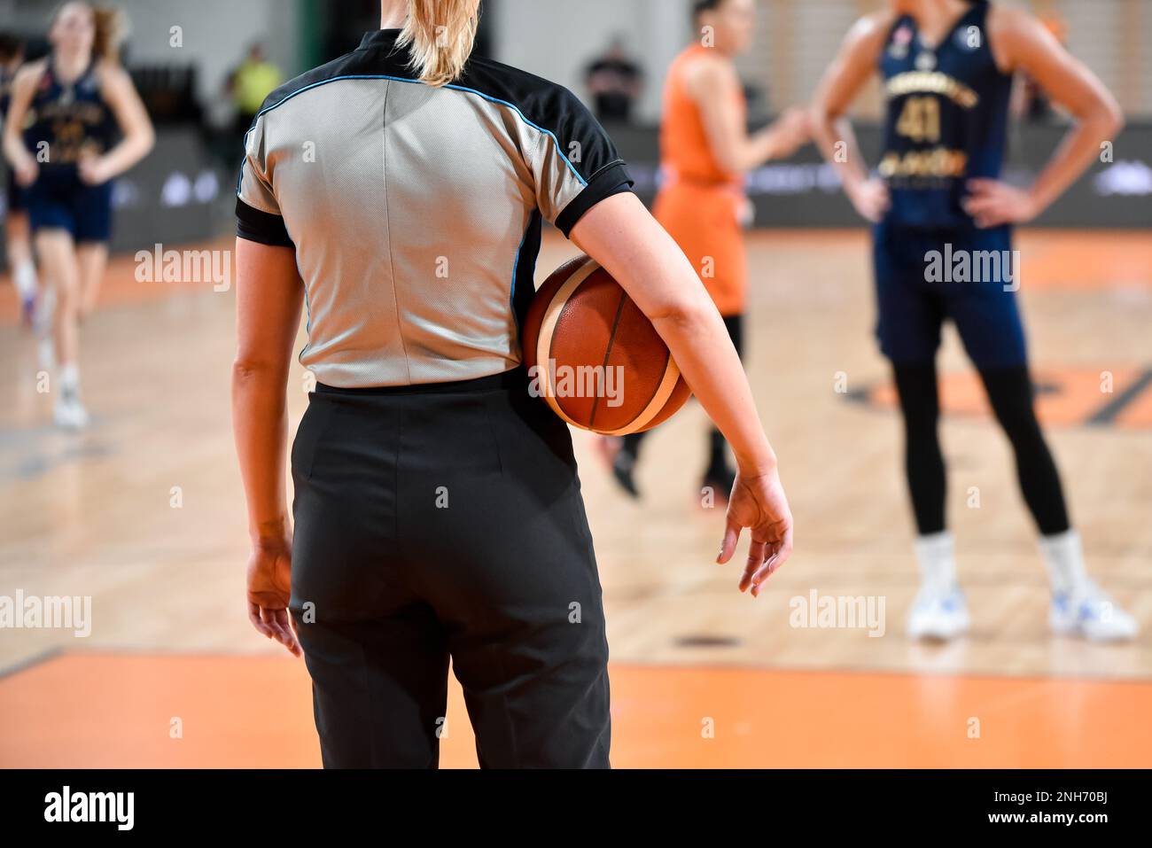 Une femme arbitre garde le ballon pendant le match de basket-ball. Banque D'Images