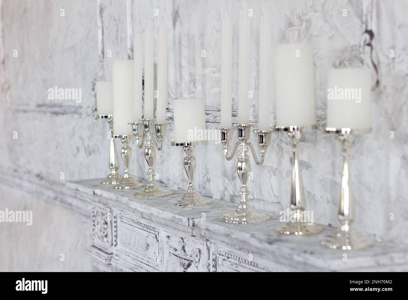 Intérieur élégant, bougies blanches dans des chandeliers élégants se tiennent sur une cheminée dans la chambre. Concentrez-vous sur le quatrième bougeoir Banque D'Images