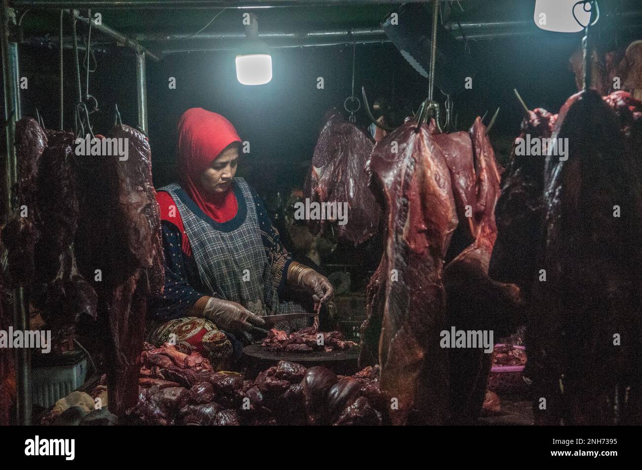 Une musulmane coupe de la viande crue sur le principal marché de gros des légumes et de la viande, Phsar Dumkor, la nuit à Phnom Penh, au Cambodge. © Kraig Lieb Banque D'Images