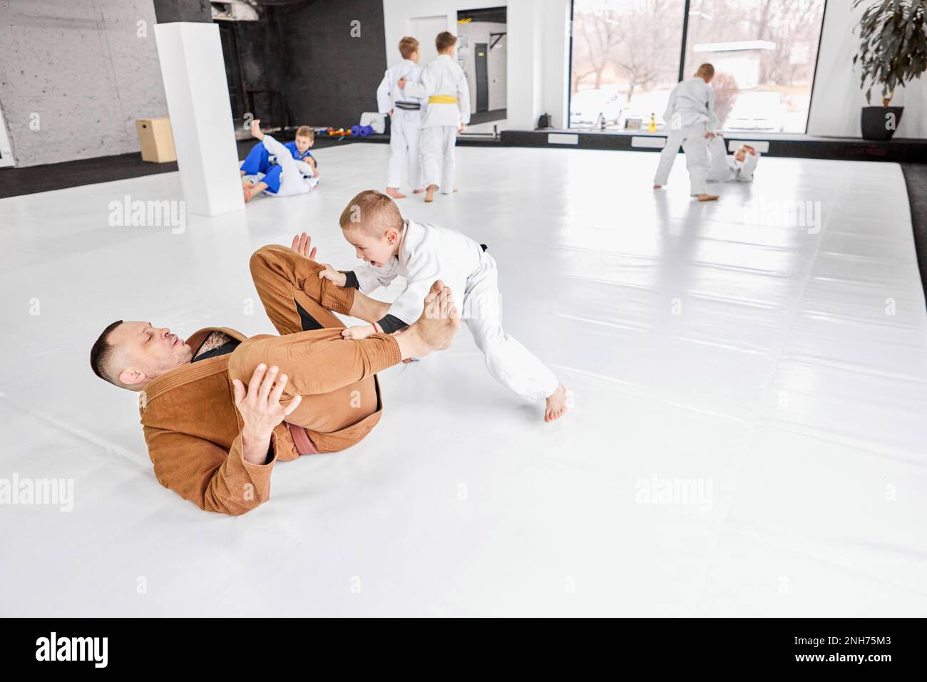 Portrait dynamique de l'homme, judo professionnel, entraînement de l'entraîneur de jiu-jitsu avec petit garçon, enfant dans un kimono blanc. Style de vie sportif Banque D'Images