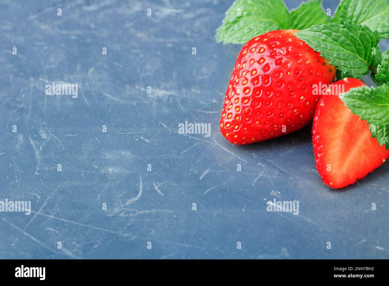 Baies de fraises fraîches avec feuilles de menthe poivrée sur fond de pierre bleue classique. Bleu classique de l'année 2020. Copier l'espace Banque D'Images