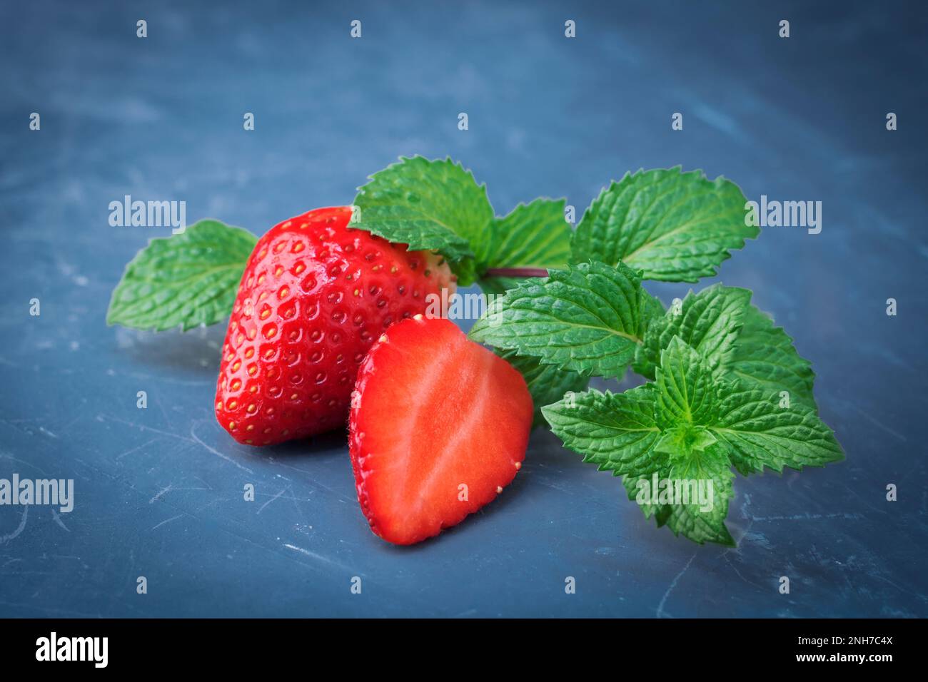 Baies de fraises fraîches avec feuilles de menthe poivrée sur fond de pierre bleue classique. Bleu classique de l'année 2020. Copier l'espace Banque D'Images