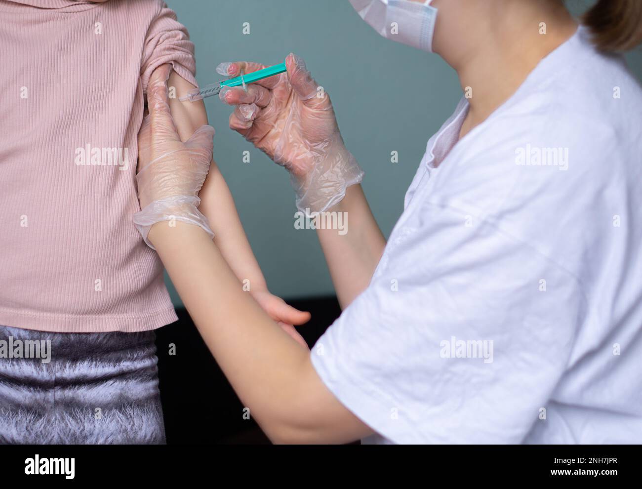 Petit enfant vacciné par un médecin dans un masque médical. Banque D'Images