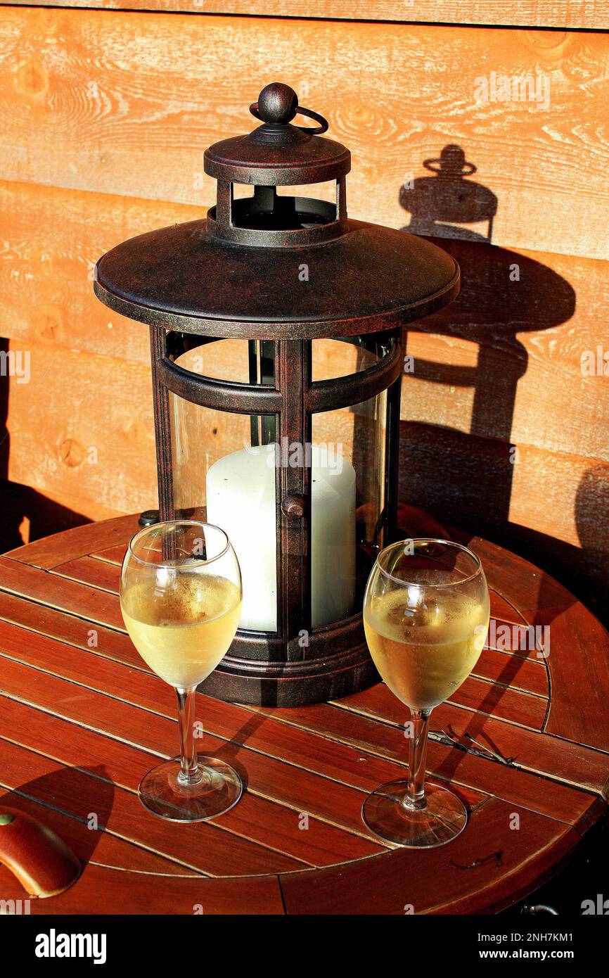 Vin blanc dans des verres à vin et un porte-bougie antique à l'extérieur sur une table de patio pendant un après-midi d'été à Atlas, Wisconsin USA. Banque D'Images
