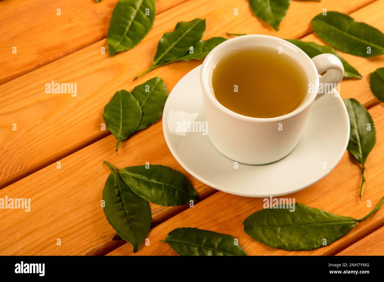 Feuilles de thé avec une tasse de thé vert, sur fond noir Banque D'Images