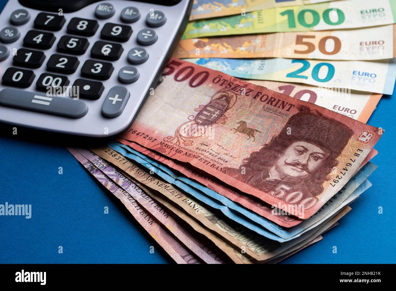 Il y a des forints hongrois et des billets en euros sur une surface plane.  À côté se trouve une calculatrice sur une table bleue. Taux de change HUF  EUR Photo Stock -