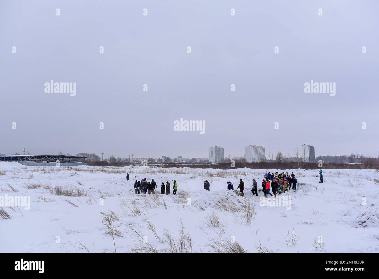 Une foule de personnes se promène dans un champ enneigé pour vérifier la piste lors d'une compétition tout-terrain en Russie en Sibérie. Banque D'Images