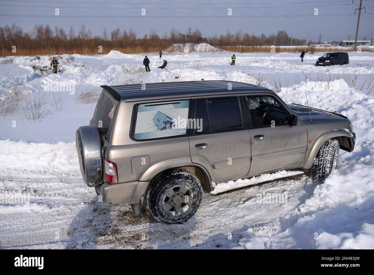 Le 4x4 de patrouille Nissan se déplace rapidement dans le champ de neige en hiver avec un passager souriant et souriant. Banque D'Images