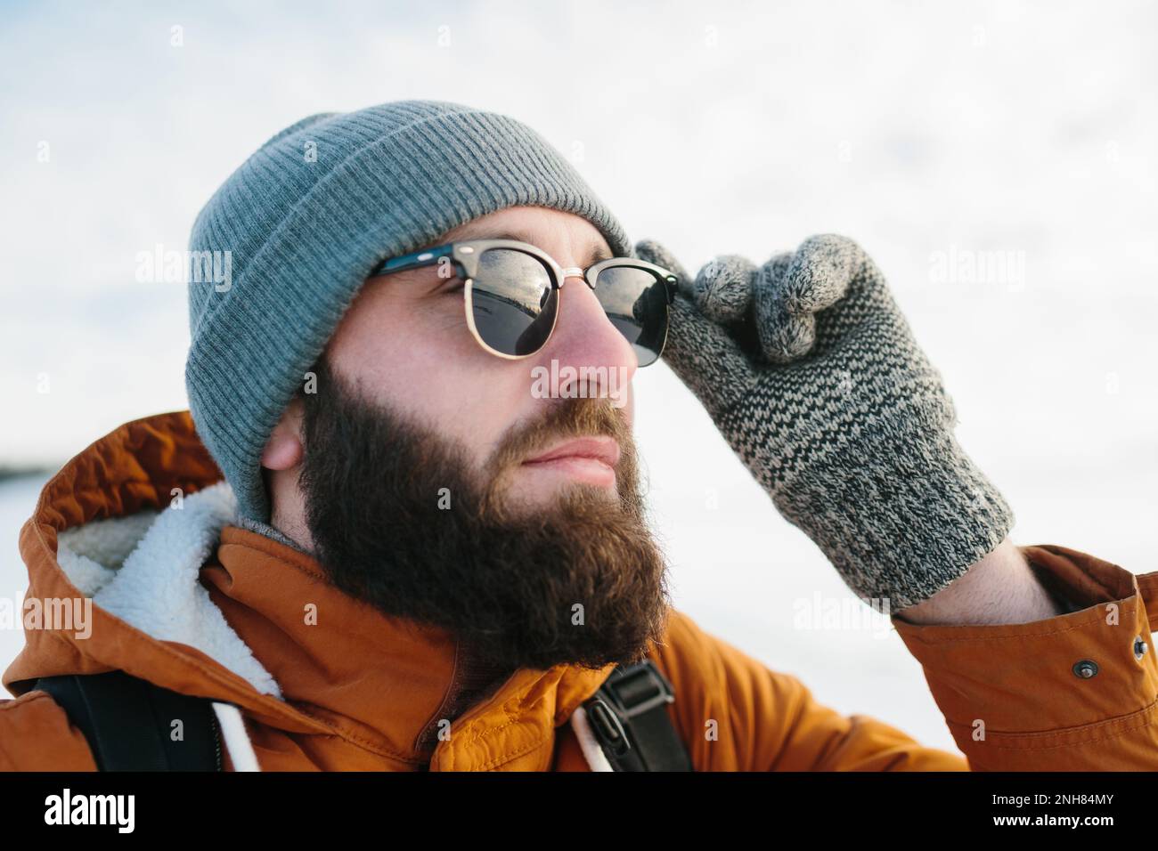 Un touriste regarde le coucher du soleil, tout en grimpant dans les montagnes d'hiver, dans des lunettes reflétant le ciel. Banque D'Images