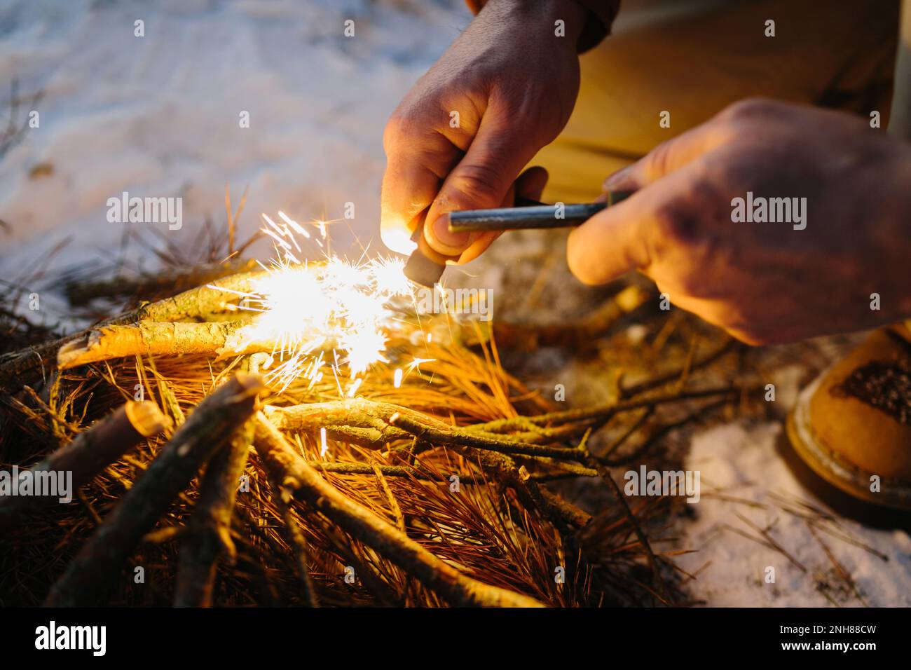 Gros plan de la main mâle commence le feu avec l'acier de feu de magnésium, gâche de feu. Concept de survie Banque D'Images