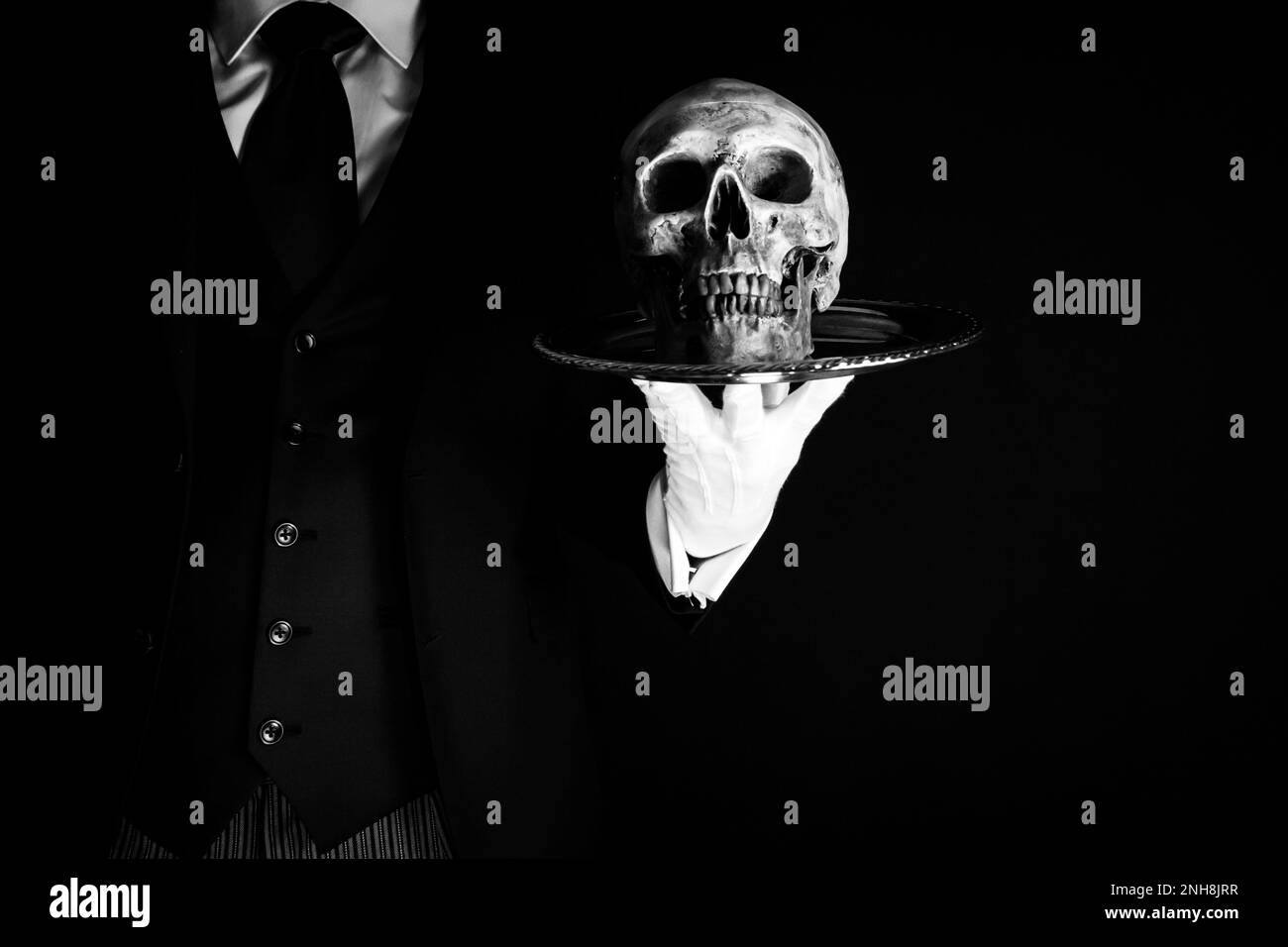 Portrait de Butler ou de garçon en costume sombre et gants blancs tenant le crâne sur le plateau. Concept de Horror et Halloween. Mort inquiétante. Banque D'Images