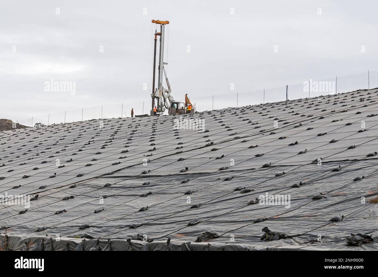 Engin de forage de puits de gaz méthane au sommet d'une colline recouverte d'une géomembrane en PVC dans une décharge active. Banque D'Images