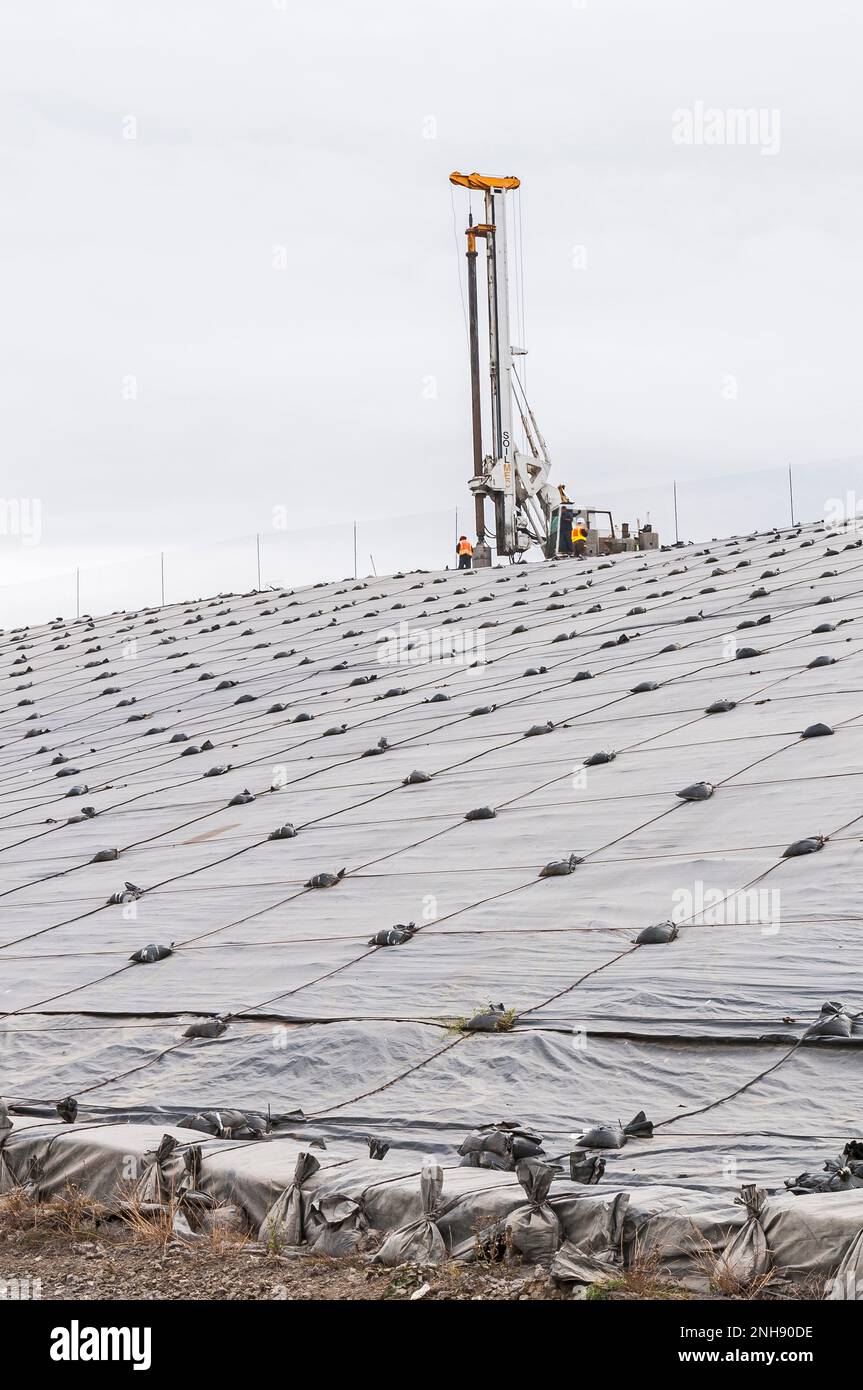 Engin de forage de puits de gaz méthane au sommet d'une colline recouverte d'une géomembrane en PVC dans une décharge active. Banque D'Images